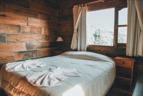1 dormitorio con 1 cama con toallas en Cabañas del Peñon 2 - 2 dorm en La Cumbrecita