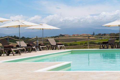 a swimming pool with chairs and umbrellas at La Casa di Spinosella in Valledoria