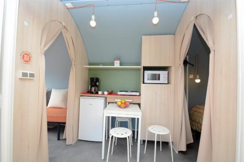 una pequeña cocina con mesa y 2 taburetes en una habitación en Les Insolites du vélodrome d'Albert en Albert