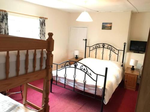 a bedroom with a bed and a tv and a window at Charming 3-Bed House on Exmoor in Minehead