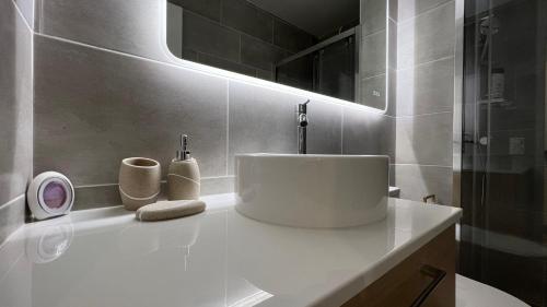 a bathroom with a white sink and a mirror at Appartement COSY, VUE MER avec Parking Privatif in Canet-en-Roussillon