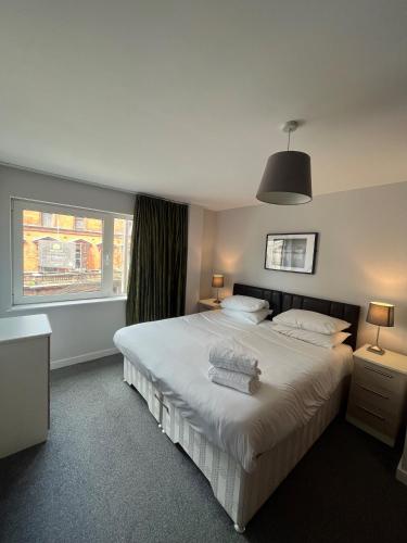 a bedroom with a large white bed and a window at Quayside Apartments by Urban Space in Cardiff