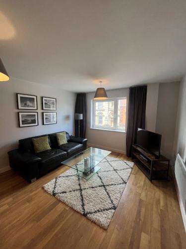 a living room with a black couch and a glass table at Quayside Apartments by Urban Space in Cardiff