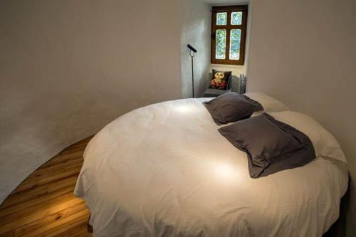 Chateau De Val في Lanobre: سرير أبيض كبير في غرفة نوم مع أرضية خشبية