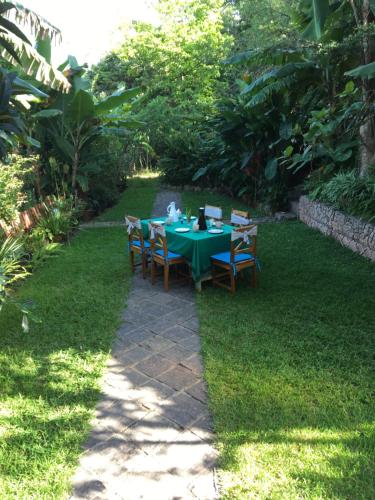 a green table with chairs in a garden at Hotel Ambalakely in Ambalakely