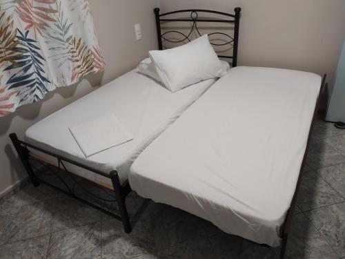 a bed with white sheets and a pillow on it at MEIMETIS GREEN HOUSE in Neapolis