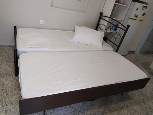 a bed with white sheets and pillows on it at MEIMETIS GREEN HOUSE in Neapolis