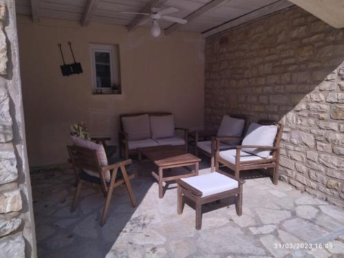 a patio with chairs and tables and a stone wall at La maison d'en haut in La Capelle-et-Masmolène