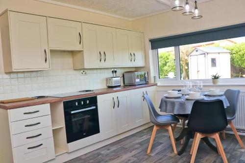 a kitchen with white cabinets and a table with chairs at Coastal retreat surrounded by open countryside in Saint Ervan