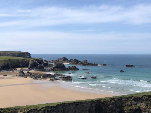 a view of a beach with rocks in the ocean at Coastal retreat surrounded by open countryside in Saint Ervan