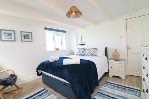 a bedroom with a bed with a blue blanket at Coastal retreat surrounded by open countryside in Saint Ervan