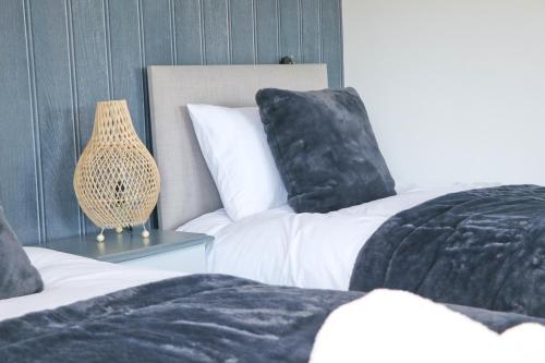 two beds with black pillows and a lamp on a table at Coastal retreat surrounded by open countryside in Saint Ervan