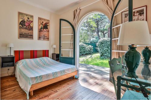 - une chambre avec un lit et une porte voûtée dans l'établissement Itsala - Hossegor agréable villa entre canal et océan à 3 minutes à pied de la plage, à Soorts-Hossegor