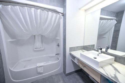 a white bathroom with a shower and a sink at Hôtel Napoléon in Angers