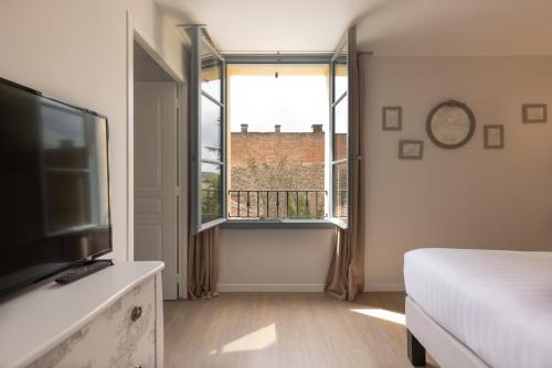 a bedroom with a bed and a large window at Hôtel-Restaurant des Augustins in Saint-Cyprien