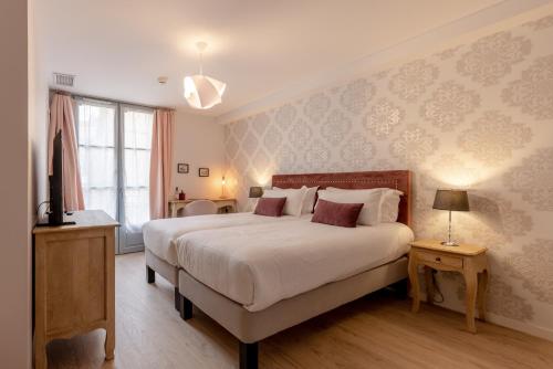 a bedroom with a large white bed and a window at Hôtel-Restaurant des Augustins in Saint-Cyprien
