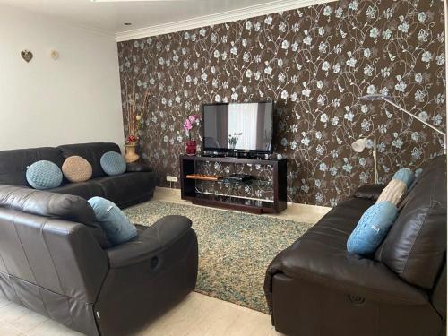 a living room with two leather couches and a television at Casa Grande in Golpilheira
