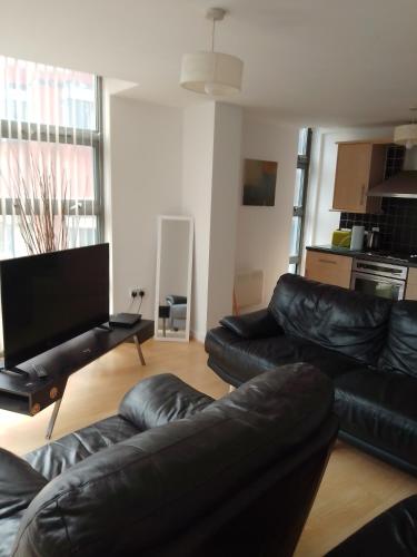 ein Wohnzimmer mit schwarzen Ledermöbeln und einem Flachbild-TV in der Unterkunft Apartment Liverpool in Liverpool