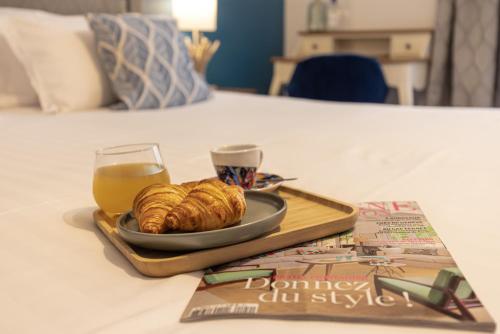 a plate of croissants and a glass of orange juice and a magazine at Hôtel-Restaurant des Augustins in Saint-Cyprien