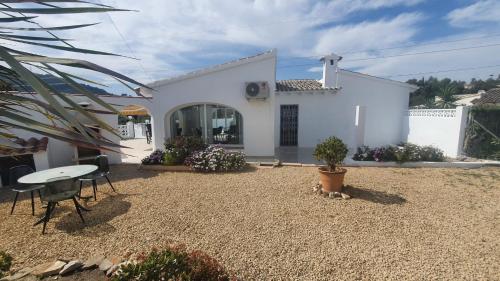 een wit huis met een tafel en stoelen in een tuin bij Cheerful 2-bedroom villa with private pool in Calpe