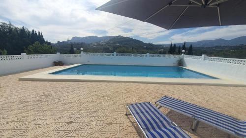 een zwembad met 2 ligstoelen en een parasol bij Cheerful 2-bedroom villa with private pool in Calpe