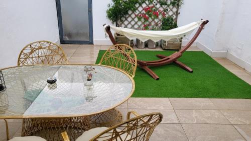 eine Terrasse mit einem Tisch, Stühlen und einer Hängematte in der Unterkunft Apartamento EL REAL - Espartinas - SEVILLA in Espartinas