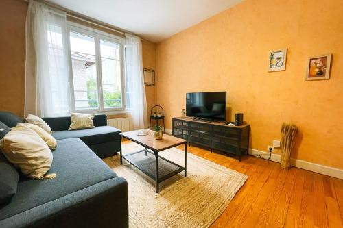 ein Wohnzimmer mit einem blauen Sofa und einem TV in der Unterkunft The Harmony of Eras #FL in Grenoble
