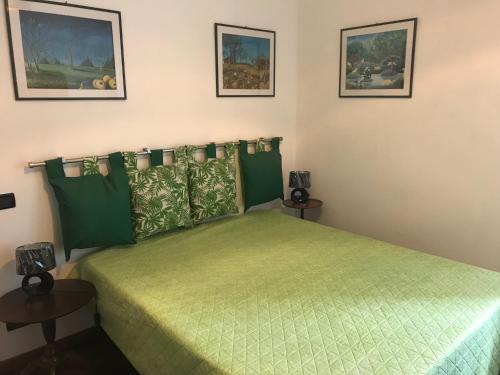 1 dormitorio con 1 cama verde y 2 mesas en Chez Christine la petite en Cogoleto