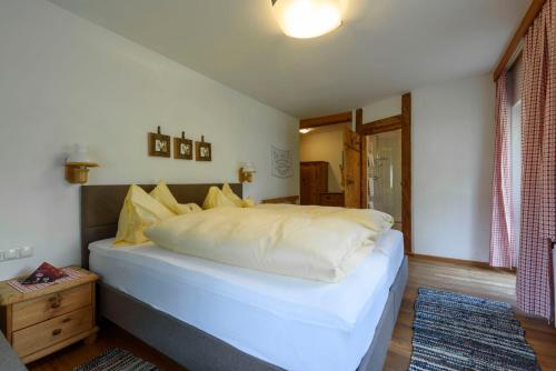 a bedroom with a bed with white sheets and yellow pillows at Gasthof Waldwirt in Russbach am Pass Gschütt