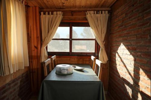 comedor con mesa y ventana en Cabañas del Peñon 3 - 1 dorm en La Cumbrecita