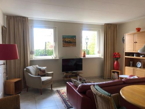 a living room with a couch and a tv at De Daalse Oase in Aalten