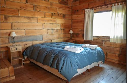 1 dormitorio con 1 cama y pared de madera en Cabañas del Peñon 3 - 1 dorm en La Cumbrecita
