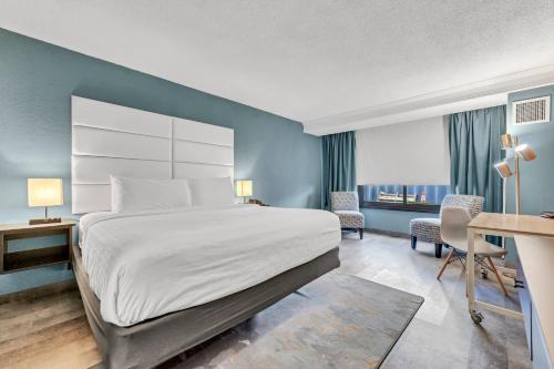 a hotel room with a large bed and a desk at Buffalo Airport Hotel in Cheektowaga