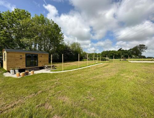 a small cabin in the middle of a field at The Stag's Head - Shepherds Hut in Great Singleton