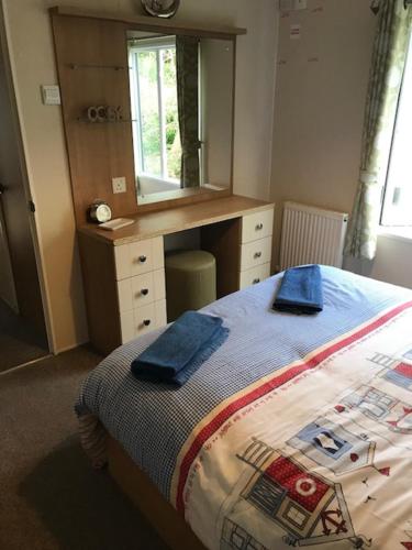 ein Schlafzimmer mit einem Bett mit einer Kommode und einem Spiegel in der Unterkunft Roslyn at Lower Hyde Park, Isle of Wight in Shanklin