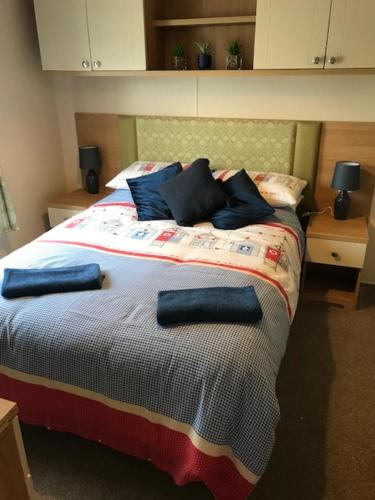 a bedroom with a bed with blue pillows on it at Roslyn at Lower Hyde Park, Isle of Wight in Shanklin