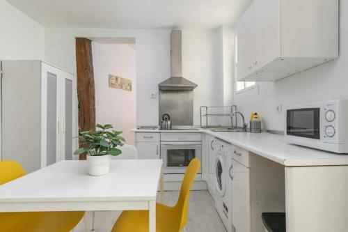 uma cozinha branca com uma mesa e cadeiras amarelas em Apartamento céntrico y confortable em Madri