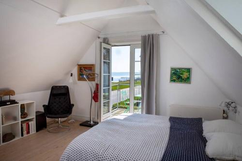 a bedroom with a bed and a chair and a window at Historical beachhouse in Snekkersten in Snekkersten