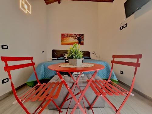 a red table with two chairs and a potted plant at La finestra sul cortile by TraMonti Apartments in LʼAquila