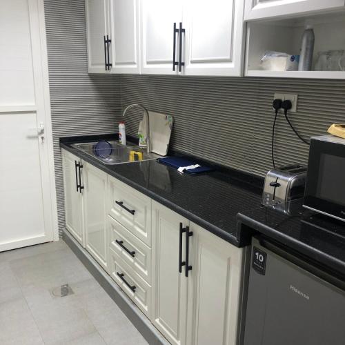 a kitchen with white cabinets and a black counter top at afnan farm in Al Ḩamrānīyah