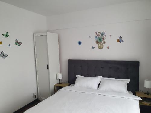 ein Schlafzimmer mit einem Bett mit weißer Bettwäsche und Schmetterlingen an der Wand in der Unterkunft Apartament SAGA in Suceava