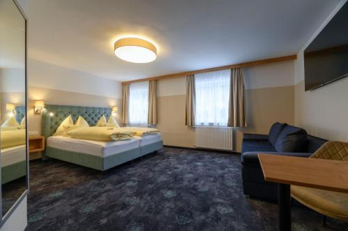 a hotel room with a bed and a couch at Gasthof Waldwirt in Russbach am Pass Gschütt