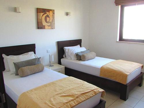 two beds in a hotel room with a window at Relaxing 2 Bed Apartment with pool view Sol Dunas in Prainha