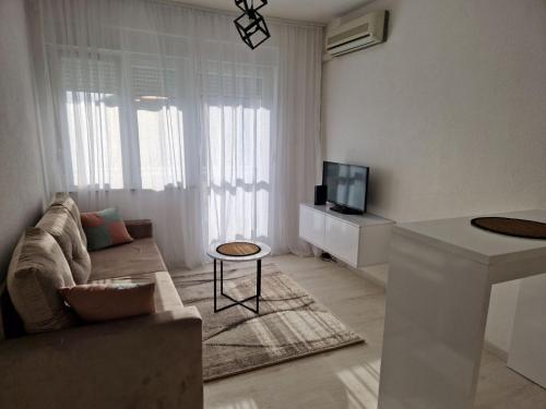 a white living room with a couch and a tv at Apartman Platan in Trebinje