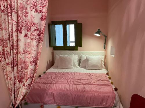 Dormitorio pequeño con cama rosa y ventana en La Casa di Vicolo Re, Vicino alla Scala dei Turchi en Porto Empedocle