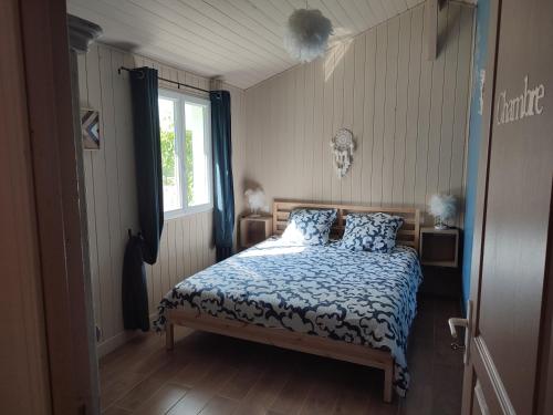 a bedroom with a bed with a blue comforter and a window at Family house carcanaise in Carcans