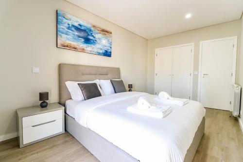 um quarto com uma grande cama branca com duas toalhas em Sunshine Apartment - Modern Ap Near the Beach em Viana do Castelo