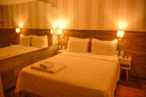 a hotel room with two beds and a mirror at Pousada da Prainha in Arraial do Cabo