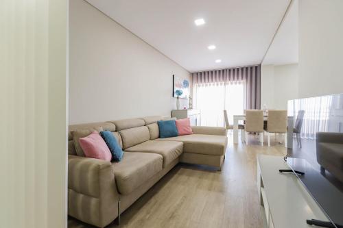 a living room with a couch with pillows on it at Sunshine Apartment - Modern Ap Near the Beach in Viana do Castelo