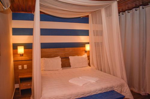 a bedroom with a canopy bed with blue and white stripes at Pousada da Prainha in Arraial do Cabo